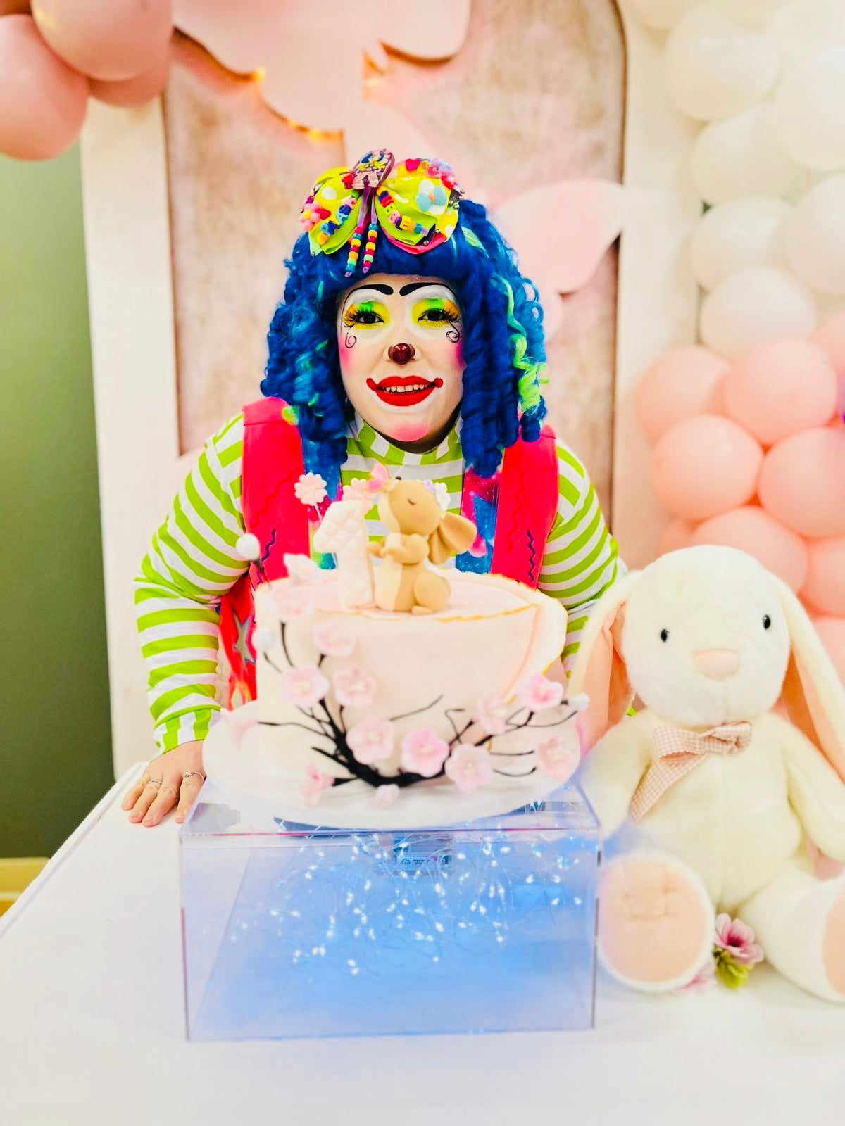 Colorful clown with a bright costume and a cake at a celebration.